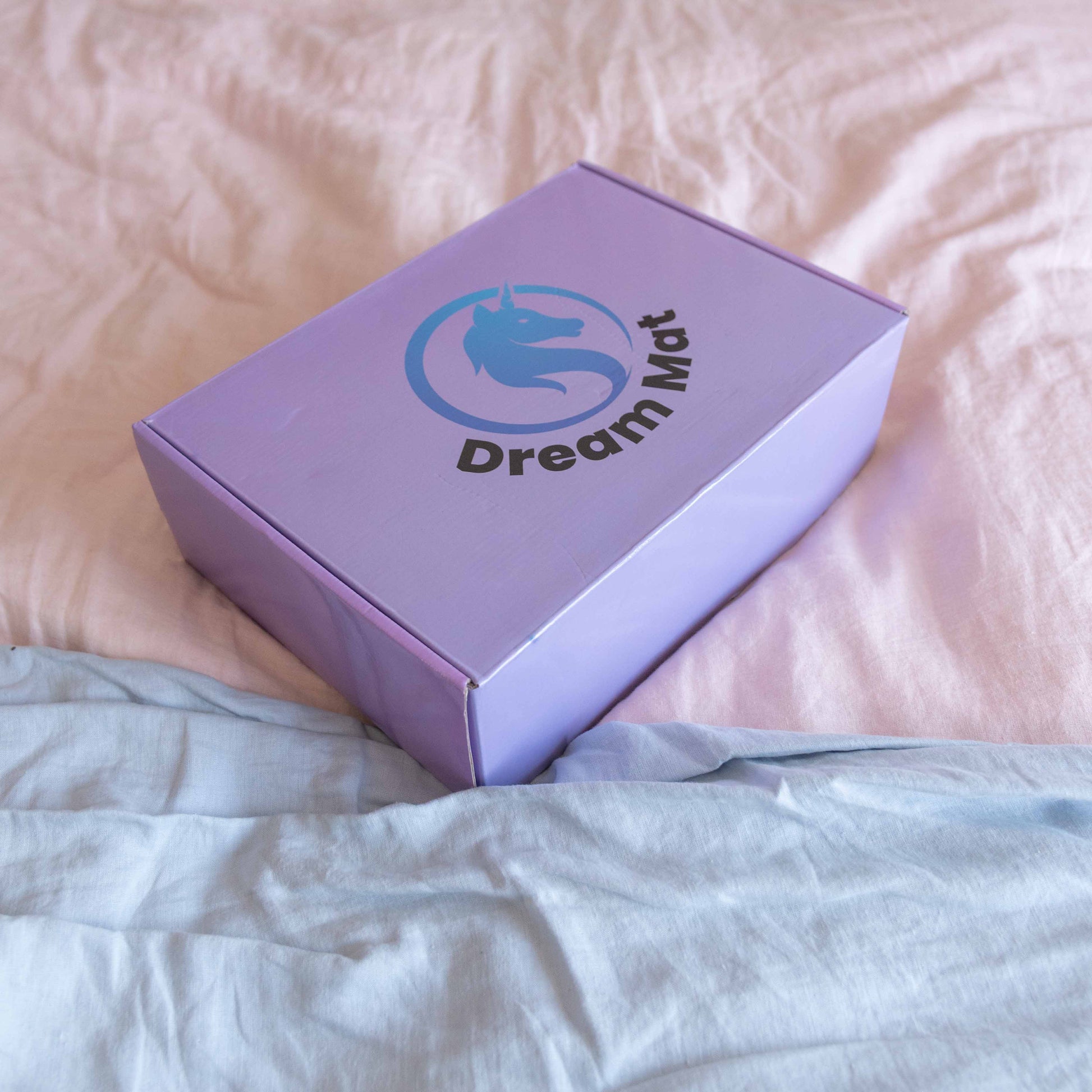 Purple box with 'Dream Mat' logo on a pink blanket